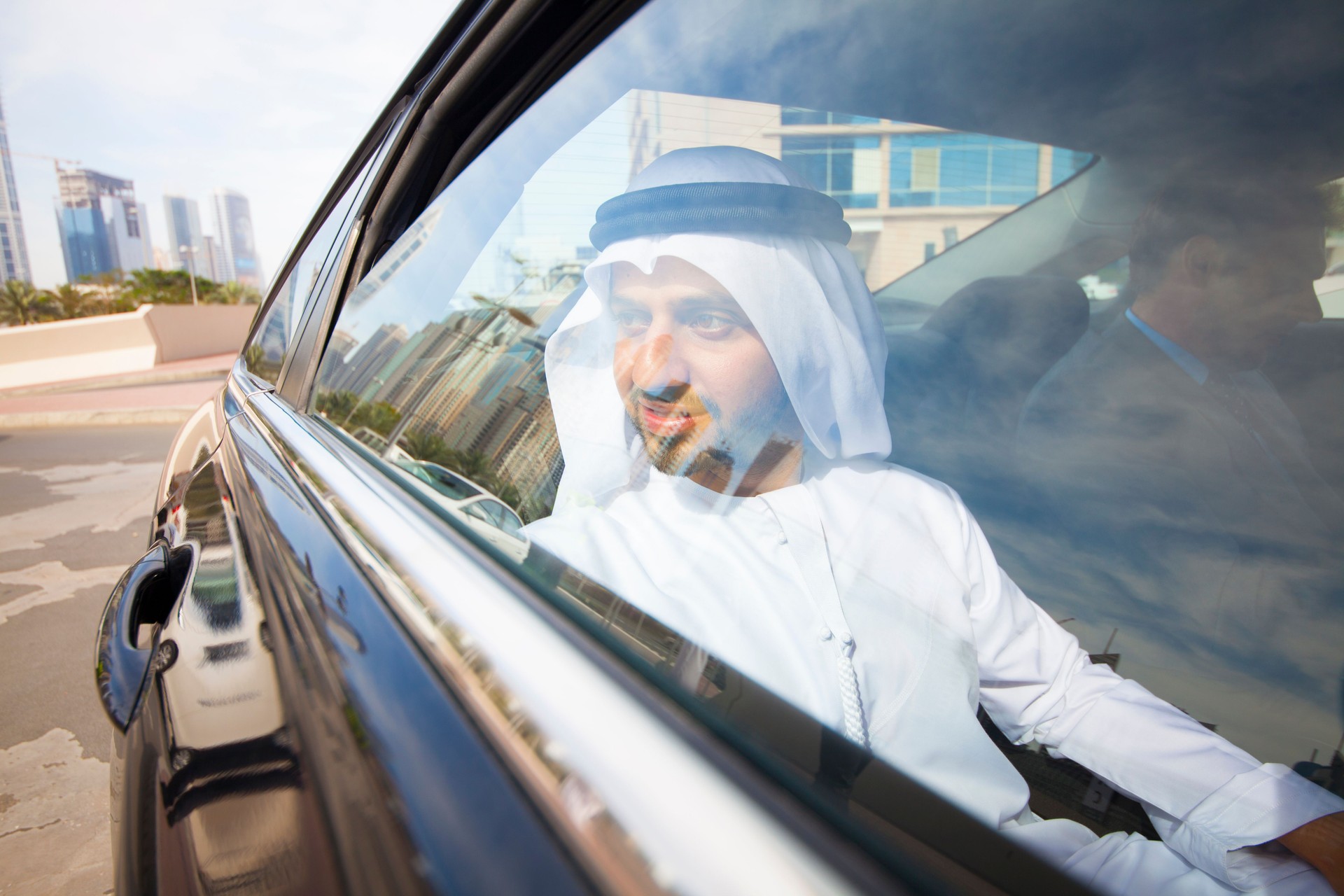 Arab and western businessmen in traditional clothes in a car